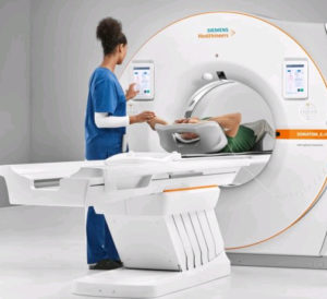 The photo shows a female technician guiding a patient into a CT scanner. 